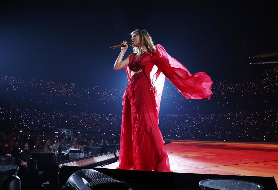 Swift, in a long red dress, sings onstage.