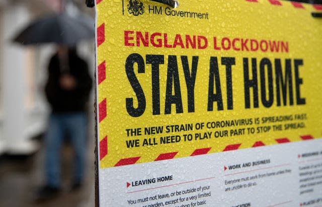 People walk past a Government sign warning people to stay at home 