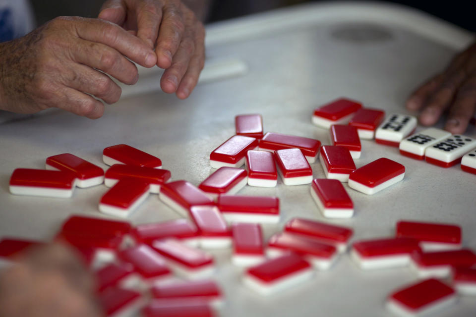 This May 2, 2014 photo shows men playing dominoes on Calle Ocho (Eighth Street) in Miami's Little Havana. Once a refuge for Cuban exiles rekindling the tastes and sounds a lost home, today Miami’s Little Havana is a mosaic of cultures and a popular tourist destination. (AP Photo/J Pat Carter)