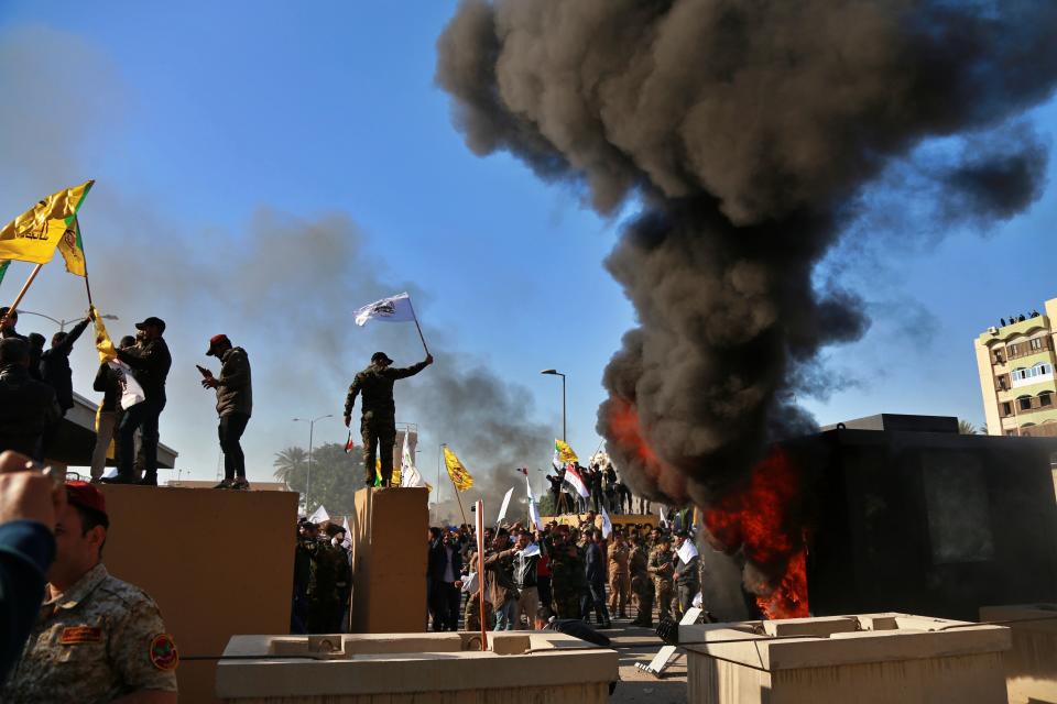 Protesters set fires in front of the U.S. embassy compound, in Baghdad, Iraq, Tuesday, Dec. 31, 2019. Dozens of angry Iraqi Shiite militia supporters broke into the U.S. Embassy compound in Baghdad on Tuesday. The breach at the embassy followed U.S. airstrikes on Sunday that killed 25 fighters of the Iran-backed militia in Iraq, the Kataeb Hezbollah. (AP Photo/Khalid Mohammed)