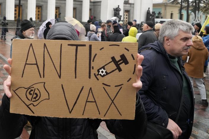 A demonstrator holds a anti-vax sign during a protest against COVID-19 restrictions and vaccine mandates in Kyiv, Ukraine, Wednesday, Nov. 3, 2021. In a bid to stem contagion, Ukrainian authorities have required teachers, government employees and other workers to get fully vaccinated by Nov. 8 or face having their salary payments suspended. In addition, proof of vaccination or a negative test is now required to board planes, trains and long-distance buses. (AP Photo/Efrem Lukatsky)
