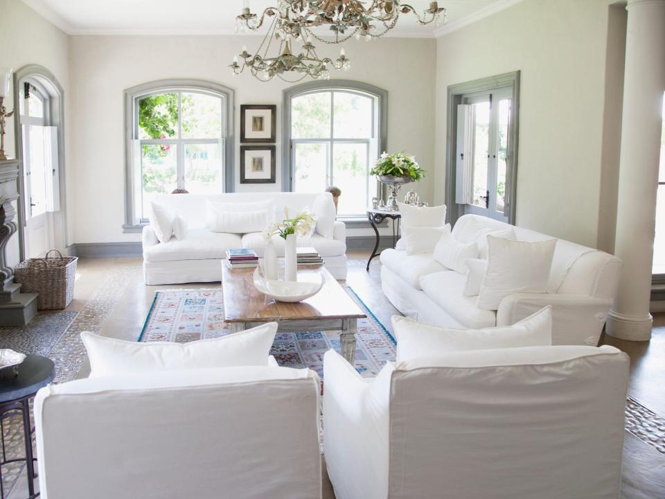 A living room with two white couches and two matching chairs.