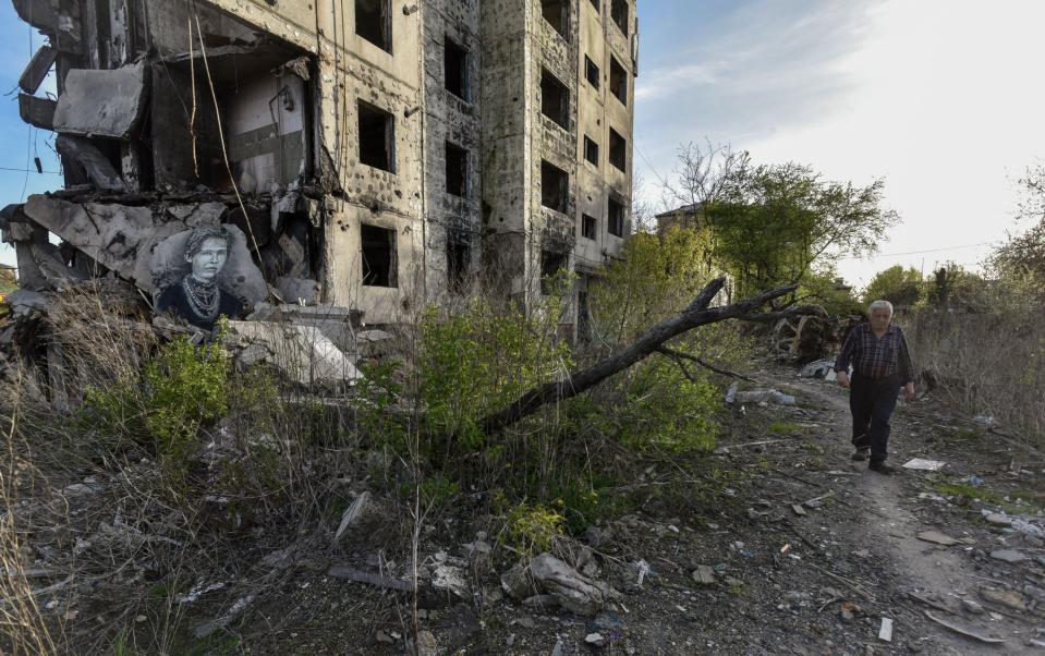 An elderly person walks along a path near a portrait of Ukrainian writer Lesia Ukrainka (L), made by street artist Christian Guemy, known as C215, on the wall of a house destroyed by Russian shelling in 2022, in Borodyanka, Kyiv region, - OLEG PETRASYUK/EPA-EFE/Shutterstock/Shutterstock