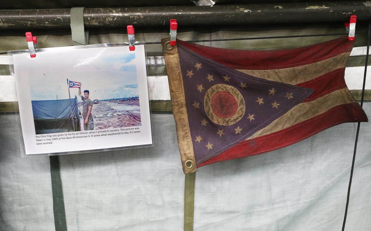 A display inside the Medic’s Corner tent at MAPS Air Museum features a 1969 photo of U.S. Army combat medic Ted Mathies holding an Ohio state flag. That original banner hangs next to the picture.