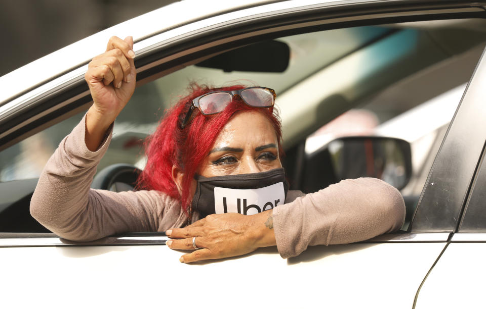 LOS ANGELES, CA - OCTOBER 08:    Rideshare driver Teresa Mercado raises her fist in support as app based gig workers held a driving demonstration with 60-70 vehicles blocking Spring Street in front of Los Angeles City Hall urging voters to vote no on Proposition 22, a November ballot measure that would classify app-based drivers as independent contractors and not employees or agents, providing them with an exemption from Californias AB 5. The action is part of a call for stronger workers rights organized by the Mobile Workers Alliance with 19,000 drivers in Southern California and over 40,000 in all of California.      Los Angeles on Thursday, Oct. 8, 2020 in Los Angeles, CA. (Al Seib / Los Angeles Times