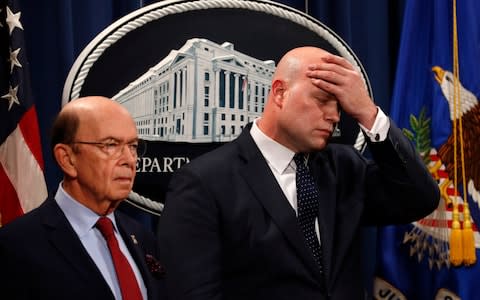 Acting Attorney General Matt Whitaker, right, wipes his brow after announcing the indictments. On the left is Commerce Secretary Wilbur Ross - Credit: AP