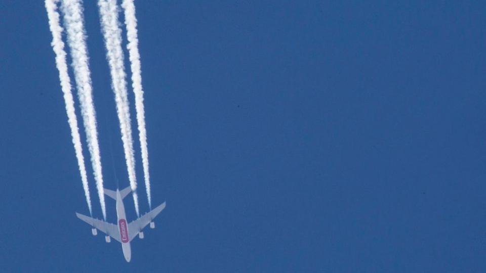Avión de Emirates deja estalas blancas en el cielo azul.