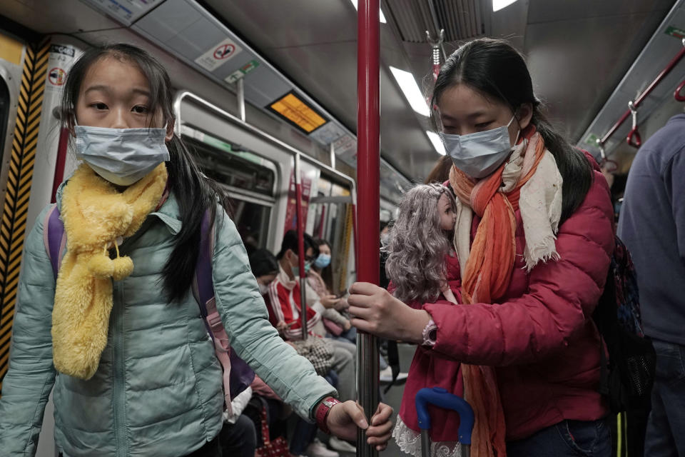 Dos niñas con mascarillas, una de ellas con una muñeca, viajan en el metro en Hong Kong, el sábado 1 de febrero de 2020. La cifra de muertos por un nuevo virus en China ha aumentado a 259 y un funcionario de la Organización Mundial de la Salud dice que otros gobiernos deben prepararse controlar "brotes locales" si la enfermedad se propaga. (AP Foto/Kin Cheung)