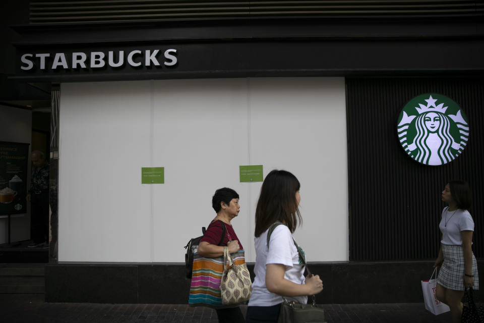 People walk past a Starbucks with barriers covering its shop windows in Hong Kong, Friday, Oct. 25, 2019. Banks, retailers, restaurants and travel agents in Hong Kong with ties to mainland China or perceived pro-Beijing ownership have fortified their facades over apparent concern about further damage after protesters trashed numerous businesses following a recent pro-democracy rally. (AP Photo/Mark Schiefelbein)