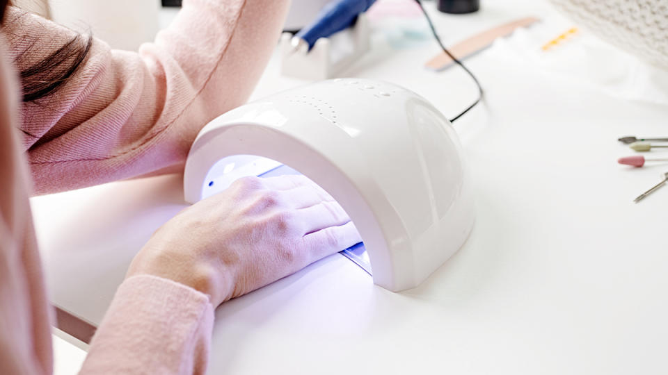 woman getting a gel manicure with her hand under the UV/LED lights