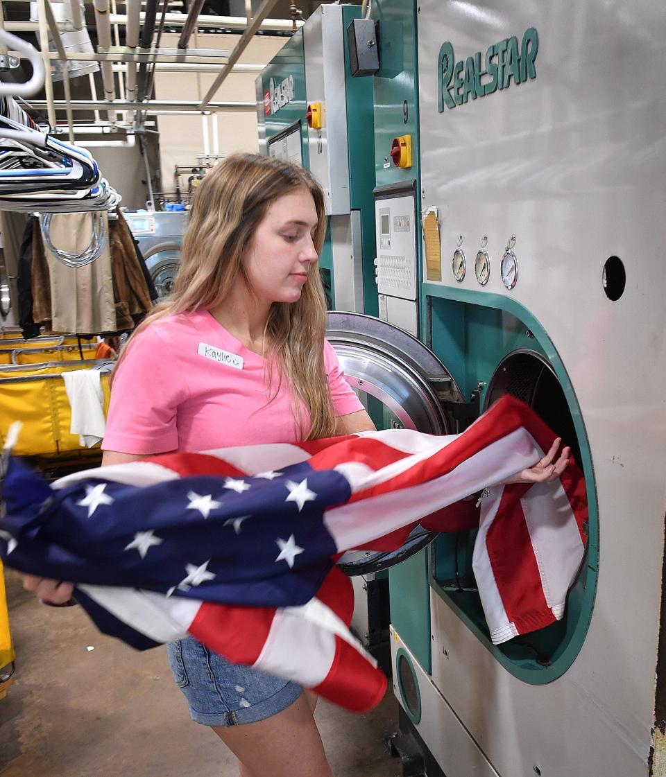 Kaylie Lange, manager of Pressed Dry Cleaners, removes an American flag from a dry cleaning machine. The company offers a free flag cleaning service year round.