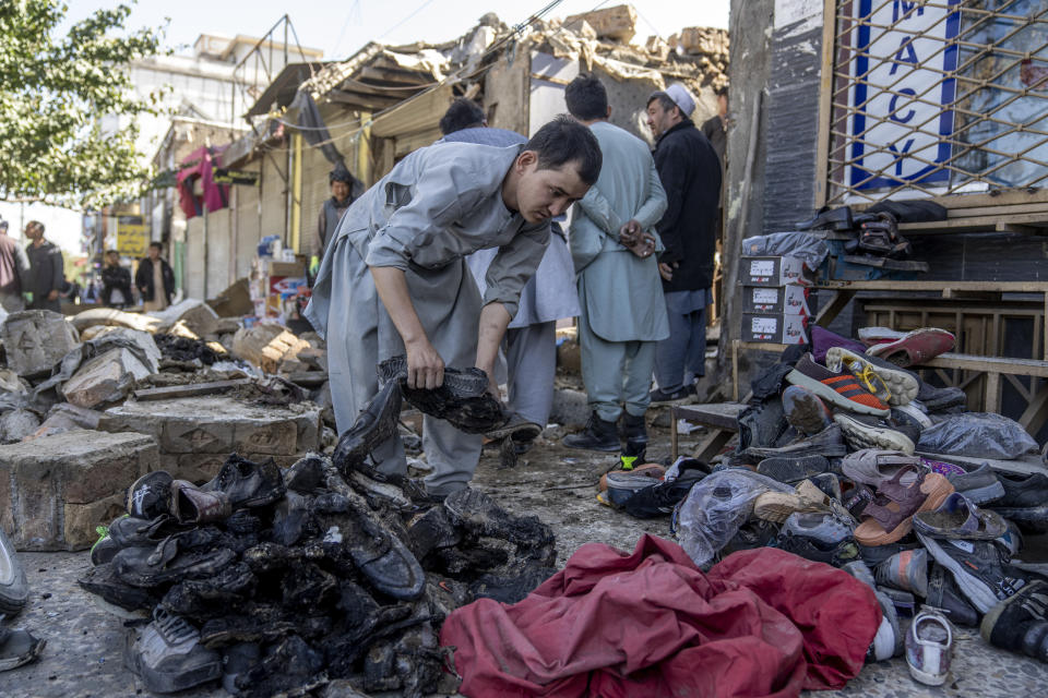 An Afghan man removes the burnt shoes in the site of an explosion in a sports club, in the west of Kabul, Afghanistan, Friday, Oct. 27, 2023. The blast killed some people and injured others in a Shiite neighbourhood in the Afghan capital Kabul. (AP Photo/Ebrahim Noroozi)