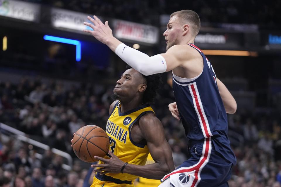 Indiana Pacers forward Aaron Nesmith, left, goes to the basket against Washington Wizards center Kristaps Porzingis, right, during the first half of an NBA basketball game, Friday, Dec. 9, 2022, in Indianapolis. (AP Photo/Darron Cummings)