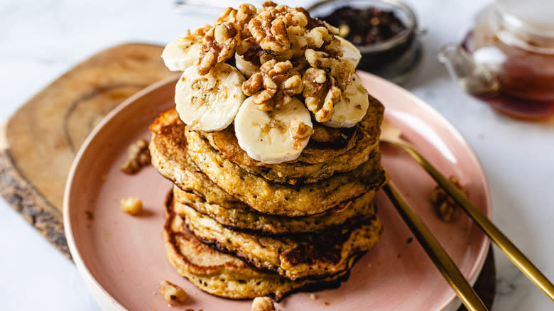 Stack of pancakes with bananas and walnuts on plate