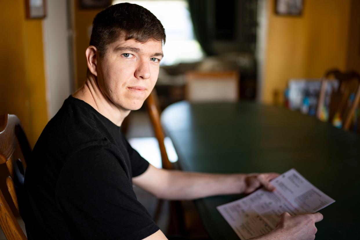 Colby Grabill, shown at his home in Des Moines, holds a medical bill with more than $1,000 in unexpected facilities fees from MercyOne.
