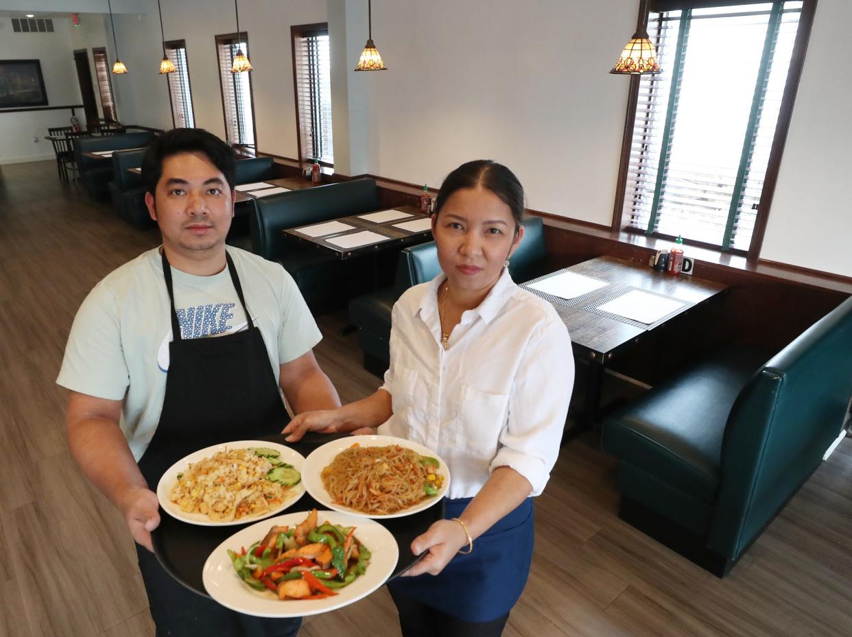 Sike and Sajin Lawi, owners of Live Mon Thai-Malay restaurant on Brittain Road, hold a trio of dishes: Malay fried black pepper salmon, chicken fried rice and Singapore noodles with tofu Nov. 29 in Akron