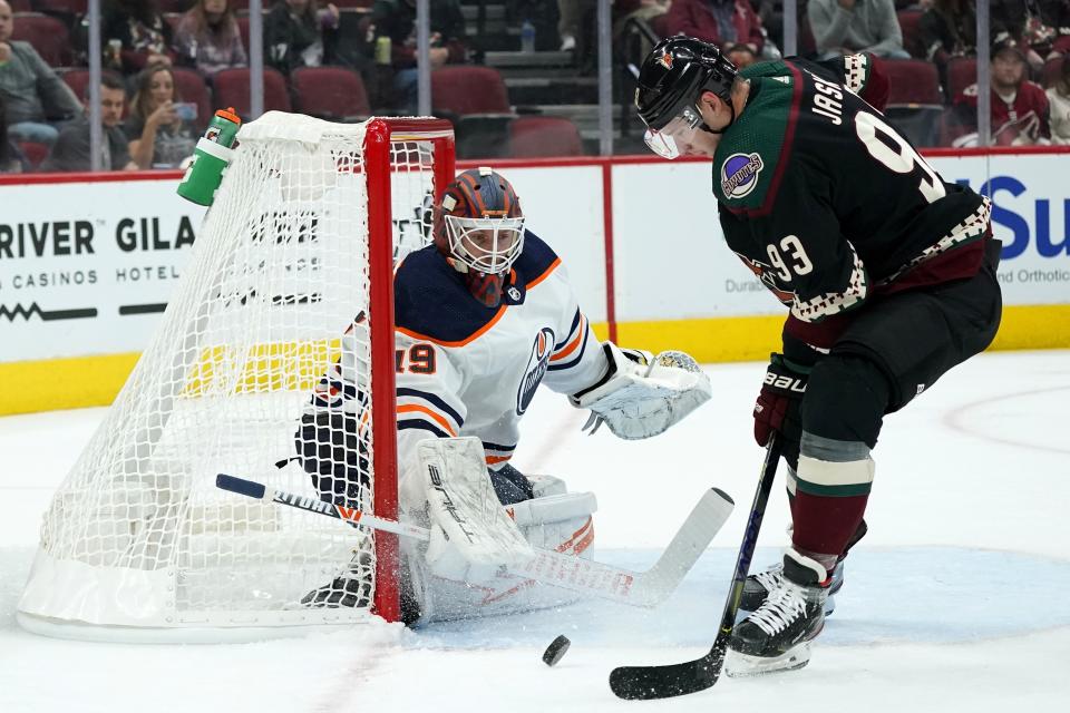 Edmonton Oilers goaltender Mikko Koskinen, left, makes a save on a shot as Arizona Coyotes right wing Dmitrij Jaskin (93) tries to control the puck during the first period of an NHL hockey game Thursday, Oct. 21, 2021, in Glendale, Ariz. (AP Photo/Ross D. Franklin)