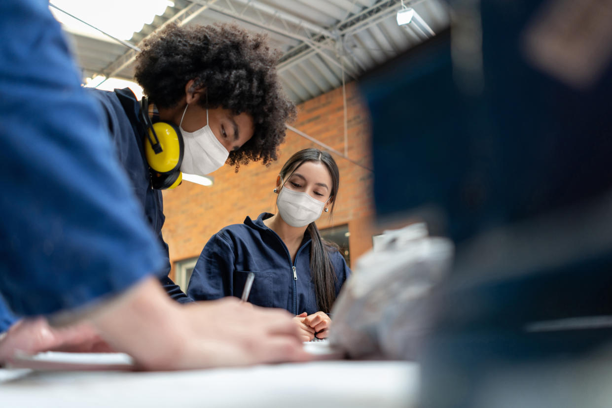 Students in a manufacturing class at school wearing facemasks during the COVID-19 pandemic - education concepts