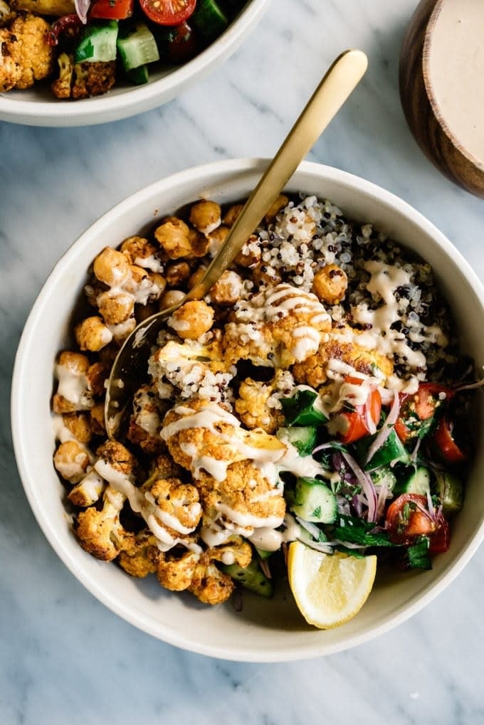 A grain bowl topped with cauliflower, veggies, and tahini.