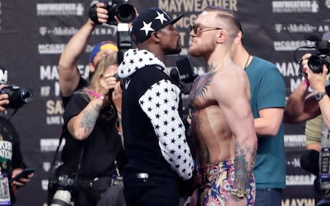 Floyd Mayweather Jr., left, and Conor McGregor, of Ireland, face each other for photos during a news conference at Barclays Center in New York - Credit:  AP