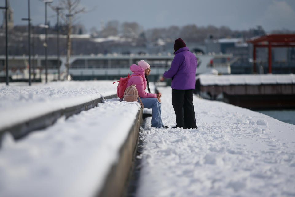 People stand over the Golden Horn at Istanbul, Tuesday, Jan. 25, 2022. Rescue crews in Istanbul and Athens on Tuesday cleared roads that had come to a standstill after a massive cold front and snowstorms hit much of Turkey and Greece, leaving countless people and vehicles in both cities stranded overnight in freezing conditions.(AP Photo/Emrah Gurel)