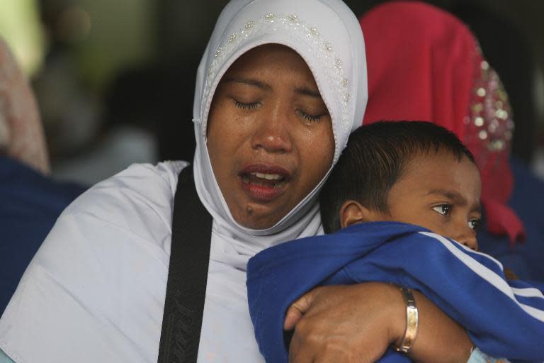 Survivors and family members of tsunami victims pray at a mass grave in Banda Aceh, northern Sumatra