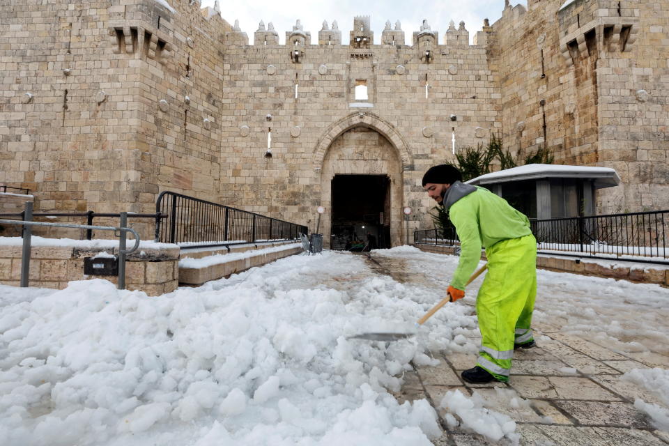 <p>A man shovels snow in front of Damascus gate in Jerusalem's Old City, January 27, 2022. REUTERS/Ammar Awad</p>
