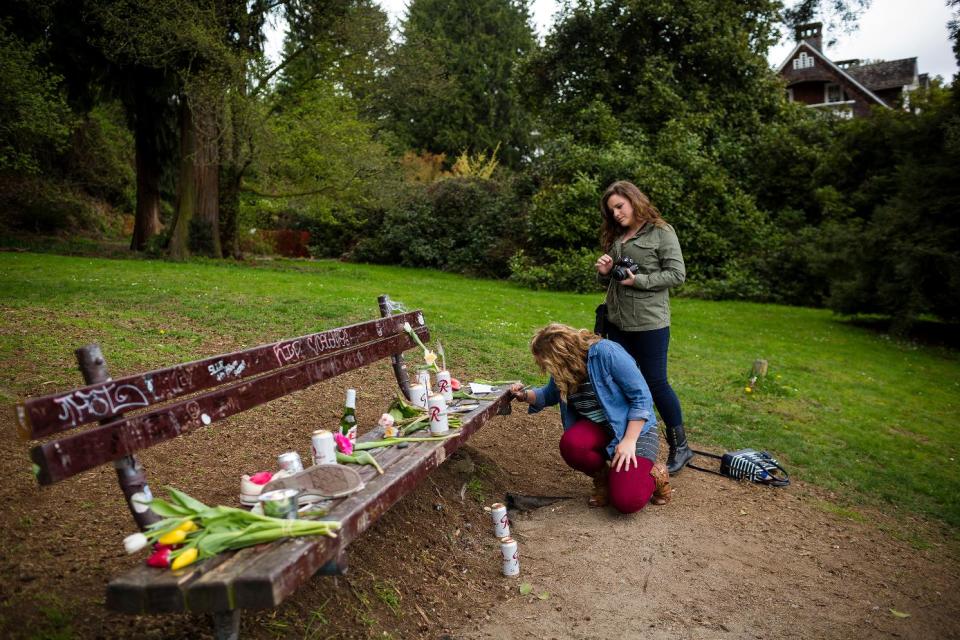 Nirvana fans who travelled from Georgia, Katlyn Reece, background, and Rachel Walraven, foreground, paid homage to the late Kurt Cobain, with handwritten notes on a bench near the home where Cobain died on the 20th anniversary of his death Saturday, April 5, 2014, at Viretta Park in Seattle, Wash. On April 10, Nirvana will be inducted into the Rock and Roll Hall of Fame. (AP Photo/seattlepi.com, Jordan Stead) MAGS OUT; NO SALES; SEATTLE TIMES OUT; MANDATORY CREDIT; TV OUT