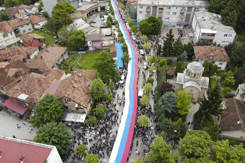 People hold a giant Serbian flag during a protest in the town of Zvecan, northern Kosovo, Wednesday, May 31, 2023. Hundreds of ethnic Serbs began gathering in front of the city hall in their repeated efforts to take over the offices of one of the municipalities where ethnic Albanian mayors took up their posts last week. (AP Photo/Bojan Slavkovic)