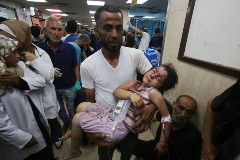 A Palestinian man carries his injured little girl to Al-Aqsa Martyrs Hospital after simultaneous Israeli attacks on Nuseirat refugee camp, al-Bureij refugee camp and al-Maghazi refugee camp.  Israeli special forces rescued four hostages from the Nuseirat refugee district in central Gaza Strip in broad daylight on Saturday after 246 days of captivity, the army said.  Omar Naaman/dpa
