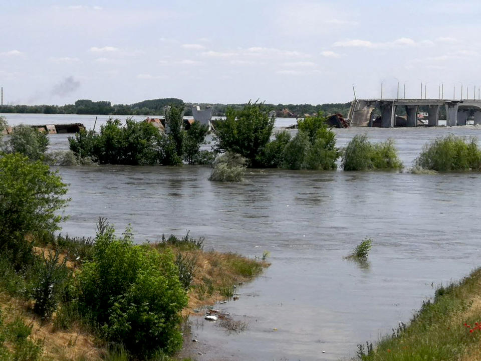 This general view shows a partially flooded area near The Antonovskiy Bridge (REAR) on the outskirts of Kherson on June 6, 2023, following damages sustained at Kakhovka hydroelectric dam. The partial destruction on June 6 of a major Russian-held dam in southern Ukraine unleashed a torrent of water that sent people fleeing flooding on the war's front line. Moscow and Kyiv traded blame for ripping a gaping hole in the Kakhovka dam as expectations built over the start of Ukraine's long-awaited offensive. (Photo by Oleg TUCHYNSKY / AFP) (Photo by OLEG TUCHYNSKY/AFP via Getty Images)