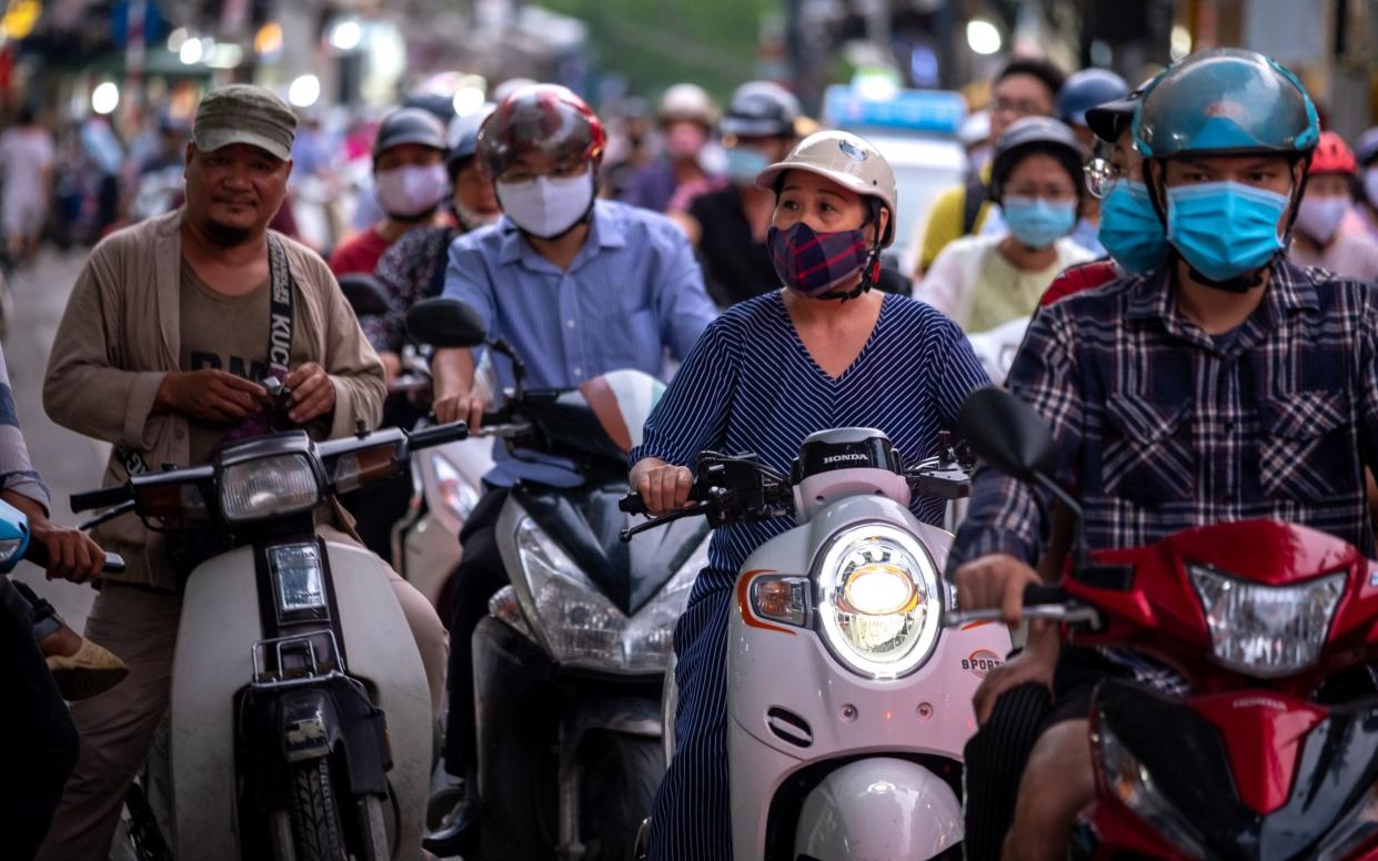 Motorcyclists wearing protective masks sit in traffic in Hanoi, Vietnam - Bloomberg