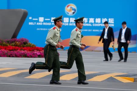 Paramilitary police officers run past the China National Convention Center, a venue of the upcoming Belt and Road Forum in Beijing, China, May 12, 2017. REUTERS/Thomas Peter