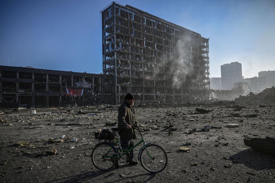 A man with his bicycle walks between debris outside the destroyed Retroville shopping mall in a residential district, after a Russian attack on the Ukranian capital Kyiv on March 21, 2022. (AFP via Getty Images)