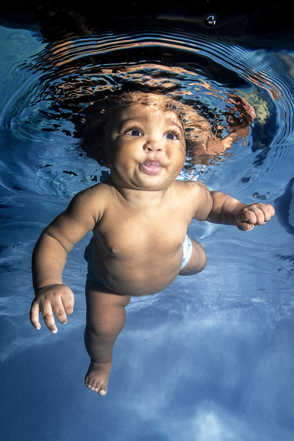 toddler swimming underwater in pool