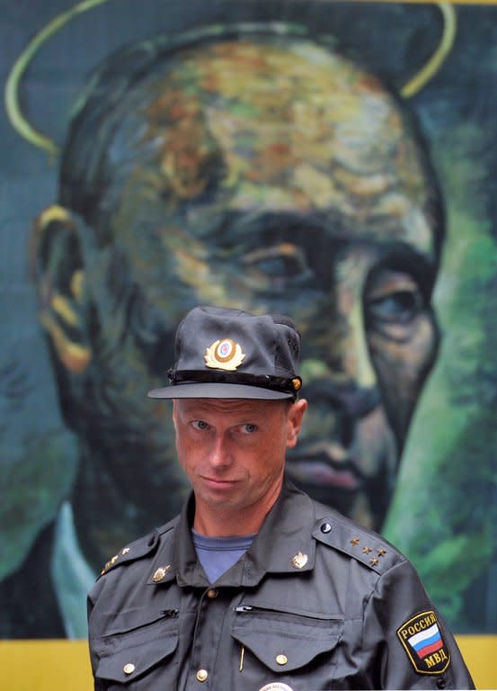 A policeman stands in front of a portrait of Russia's President Vladimir Putin by Russian artist Konstantin Altunin, during the "Leaders" exhibition in central St. Petersburg on August 24, 2013. Russian police said Wednesday they had raided an exhibition and confiscated a painting that portrayed President Vladimir Putin and Prime Minister Dmitry Medvedev lounging together in women's lingerie