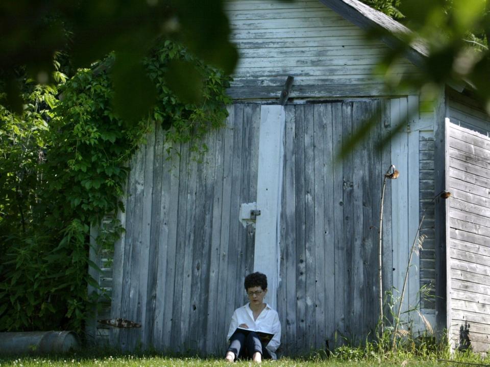 A woman sits in front of a barn in Stockholm, Wisconsin.