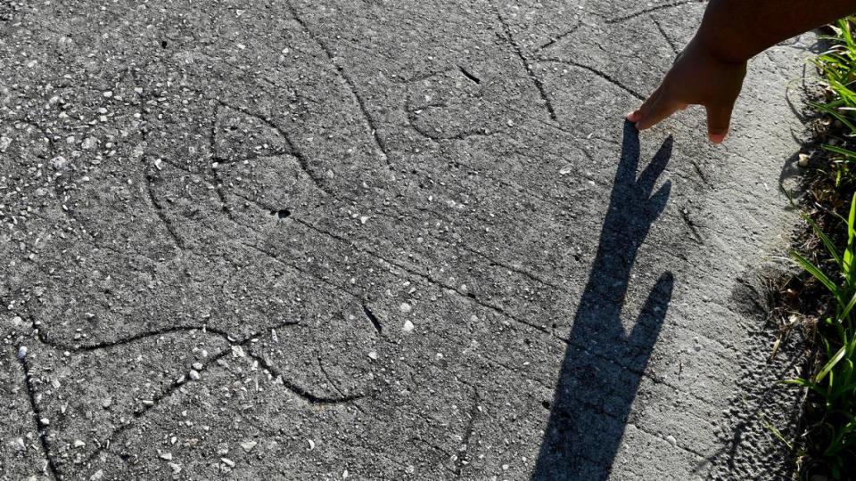 Malekia McKinney’s hand casts a shadow in front of the home where she and her sister, Maya, carved their names into the sidewalk in St. Petersburg. The home is no longer there. The city bought the property after it was foreclosed upon for unpaid code enforcement fines.