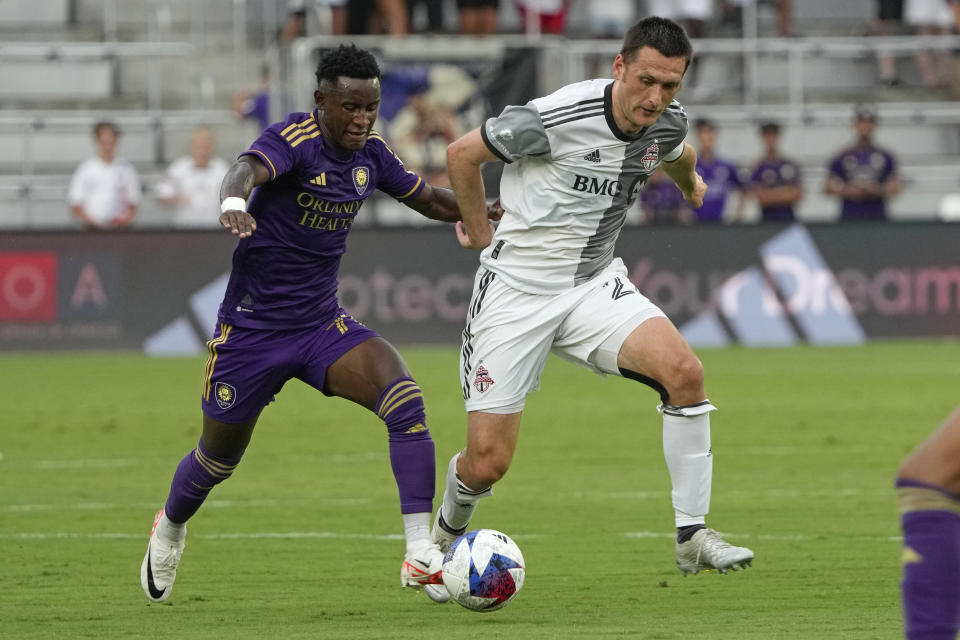 Orlando City's Ivan Angulo, left, tries to stop Toronto FC's Shane O'Neill from advancing the balll during the first half of an MLS soccer match Tuesday, July 4, 2023, in Orlando, Fla. (AP Photo/John Raoux)