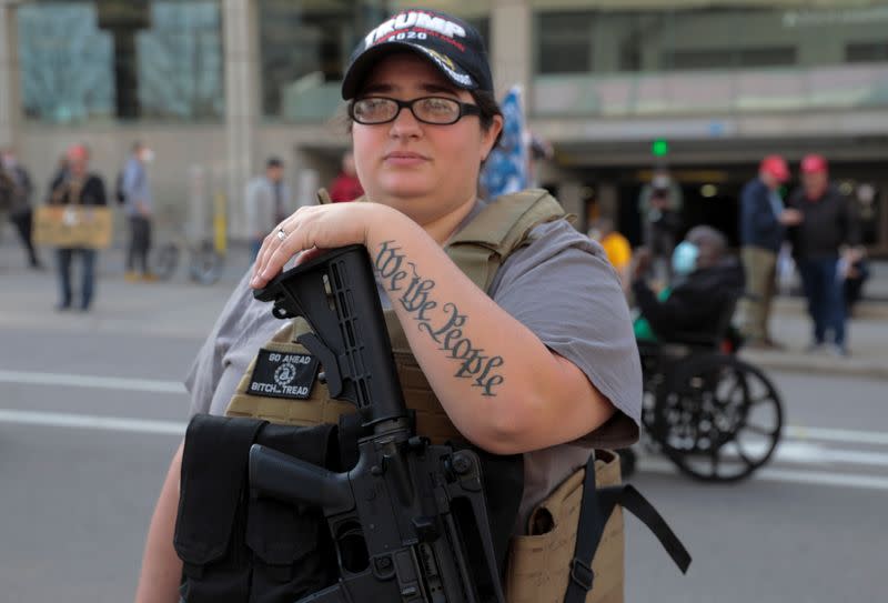 A woman carries a weapon as supporters of U.S. President Donald Trump protest the election outside the TCF Center in Detroit