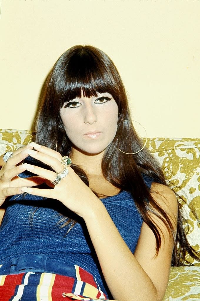 cher in 1968 sitting on a couch with her hands crossed