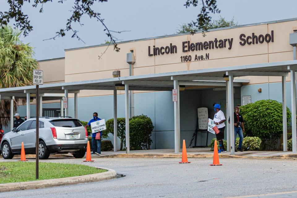 Staff members at Lincoln Elementary School await students at the parent drop off with welcoming signs on Monday, Sept. 21, 2020. The school is located just north of MLK Jr. Boulevard in Riviera Beach.