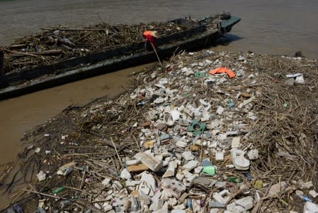 A worker collects garbage left on the bank of Yangtze River after floodwaters receded in Chongqing