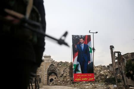 A Syrian army soldier stands guard as a poster depicting Syria's President Bashar al-Assad is seen in the background in the Old City of Aleppo, Syria January 31, 2017. REUTERS/Ali Hashisho/Files
