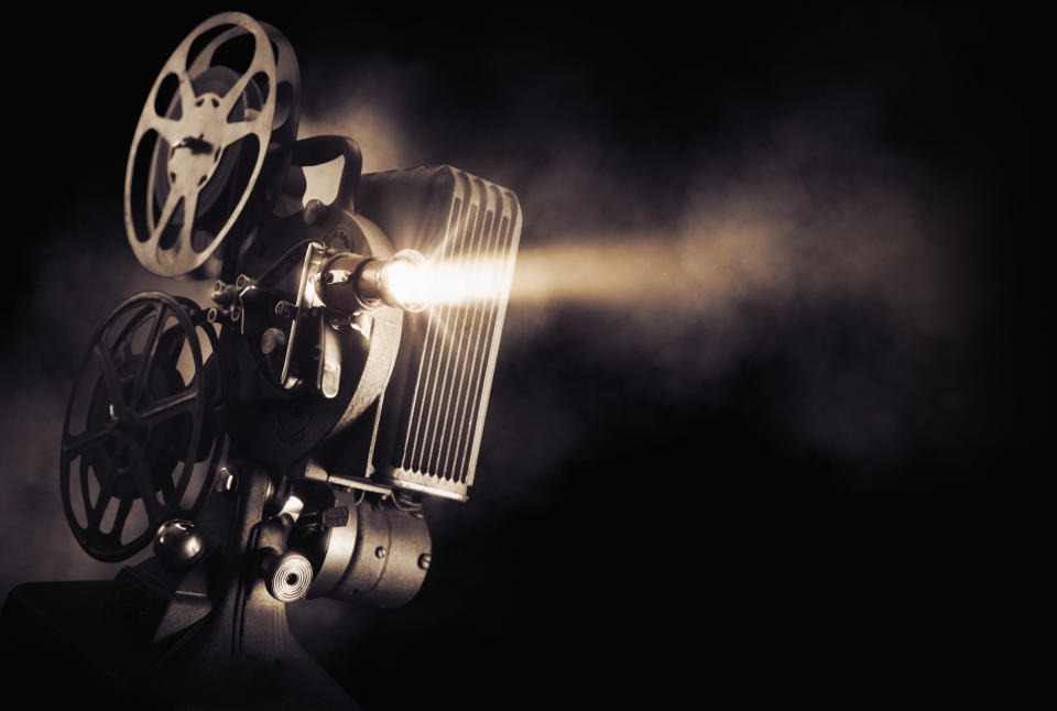 A film projector beams light out against a black background.