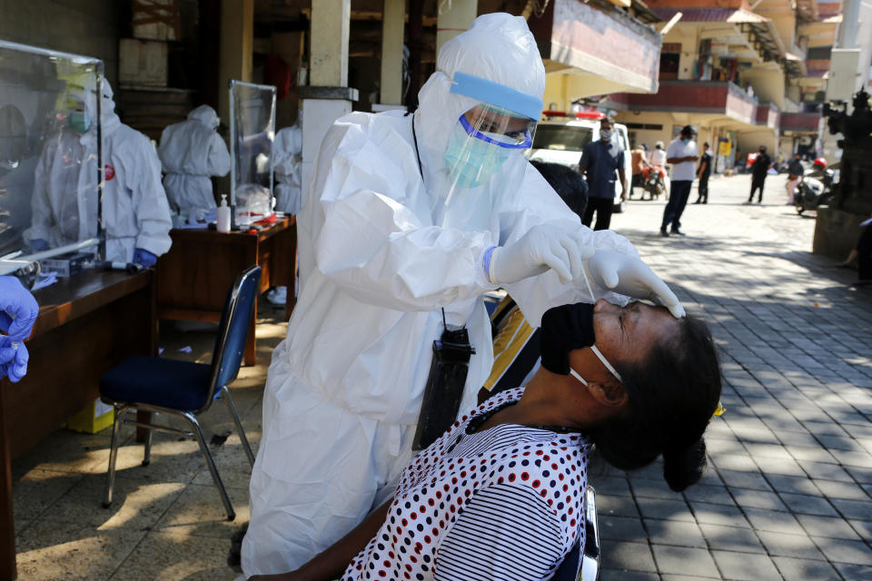 A heath worker takes a nasal swab sample during a public testing for the new coronavirus conducted at a market in Bali, Indonesia on Friday, June 12, 2020. (AP Photo/Firdia Lisnawati)