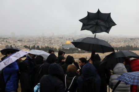People hold umbrellas as rain falls at an observation point overlooking the Dome of the Rock and Jerusalem's Old City December 6, 2017. REUTERS/Ammar Awad