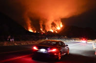 Motorists make their way along a road as the Ranch Fire burns, Thursday, Aug. 13, 2020, in Azusa, Calif. Heat wave conditions were making difficult work for fire crews battling brush fires and wildfires across Southern California. (AP Photo/Marcio Jose Sanchez)