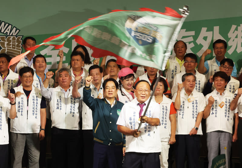 全國嘉義旅外鄉親挺賴後援會成立　現場揮舞戰旗 民進黨總統參選人賴清德（中左深色衣者）22日下午 在新北市新莊區出席「全國嘉義旅外鄉親賴清德後援 會」成立大會並授旗，振臂與眾人齊呼口號展現團結 氣勢。 中央社記者趙世勳攝　112年7月22日 