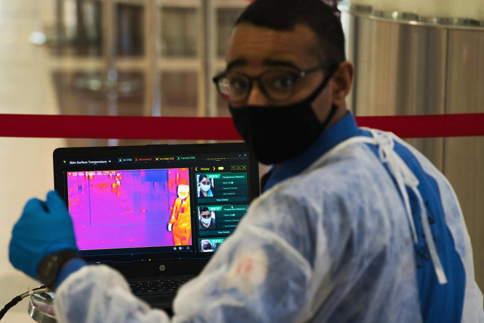 An official wearing a mask due to the coronavirus pandemic operates a temperature screening point at Dubai International Airport's Terminal 3 in Dubai, United Arab Emirates, Wednesday, June 10, 2020. The coronavirus pandemic has hit global aviation hard, particularly at Dubai International Airport, the world's busiest for international travel, due to restrictions on global movement over the virus. (AP Photo/Jon Gambrell)